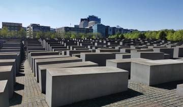 Memorial with concrete slabs and modern buildings in the background.