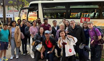 Group of people posing in front of a bus, likely on a tour.
