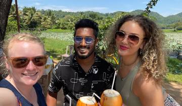 Three people holding coconuts with a lush background.
