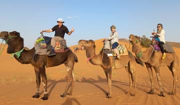 People riding camels in the desert.