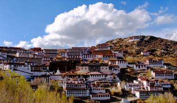 Monasteries built into a mountainside under a blue sky.