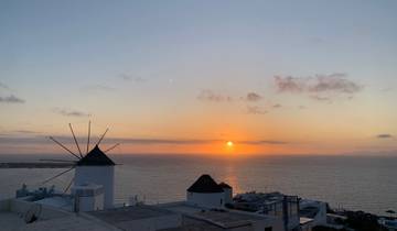 Scenic view of a windmill and ocean at sunset.