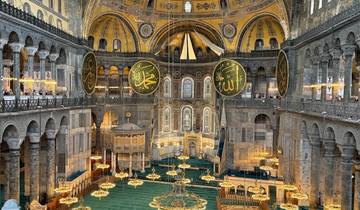 Interior view of a grand mosque with chandeliers and ornate decorations.