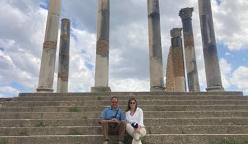 Two people sitting on a stone staircase with ancient columns in the background.