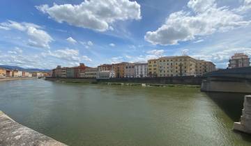 River with colorful buildings under a cloudy sky.