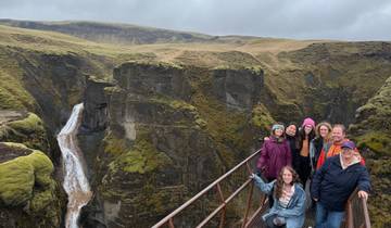 Group of people posing on a bridge with a mossy canyon backdrop.