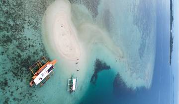 Aerial view of a sandbar with boats in turquoise water.