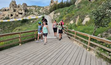 Group of people walking on a wooden path in a hilly area.