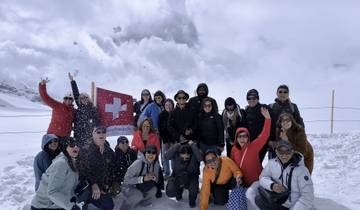 Group of people posing in the snow under a Swiss flag.