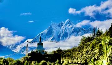 Snow-capped mountains with a stupa and prayer flags in the foreground.
