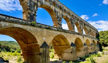 An ancient Roman aqueduct with multiple arches under a bright blue sky.
