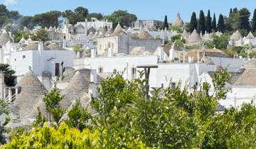 Traditional trulli houses under a clear blue sky.