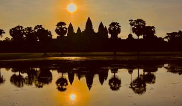Silhouette of Angkor Wat with reflection on the water during sunset.