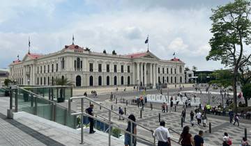 Large governmental building with flags and people in front.