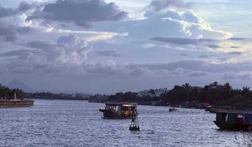 Boats on a river at dusk with a cloudy sky.