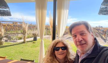 A couple enjoying a view from a vineyard with mountains in the distance.