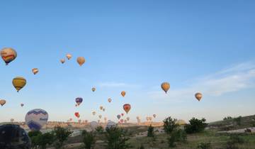 Numerous hot air balloons in the sky during early morning.