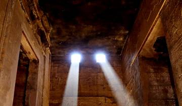 Interior of an ancient temple with beams of light streaming through small windows.