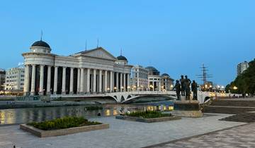 Panoramic view of a grand building with river and statues.