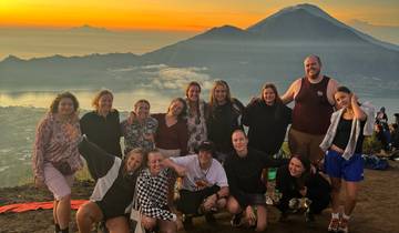 Group of people posing on a mountain with a stunning view at sunrise.