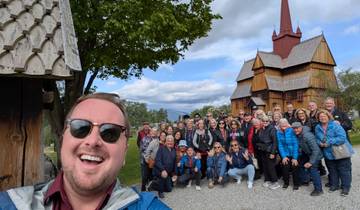 A group of tourists posing in front of a wooden church.