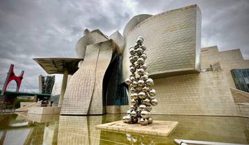 The Guggenheim Museum in Bilbao with reflective sculptures outside.