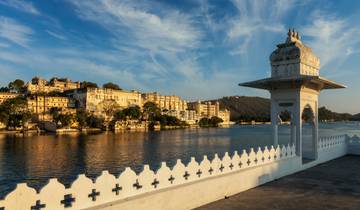 Stunning view of Udaipur City Palace by the lake at sunset.