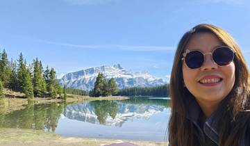 Woman posing in front of lake with mountain background.