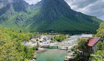 Mountain valley with bridge and parked cars.