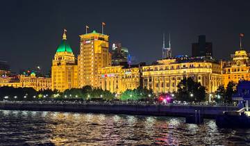 Night view of the Bund in Shanghai with illuminated buildings and reflections on the river.