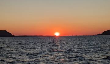 A beautiful sunset over the sea with boats visible on the horizon.