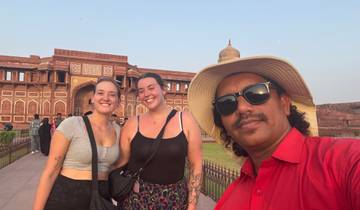 Three people standing in front of an ancient fort during sunset.