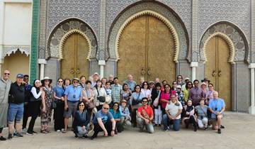 Group posing in front of an ornate entrance with golden doors.