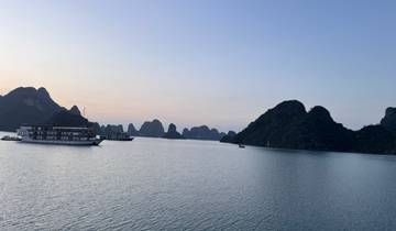 Boats in a bay surrounded by limestone karsts at sunset.