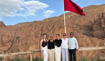 Group of people posing with a flag in a rocky landscape.