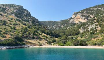 A secluded beach surrounded by green hills and clear blue water.