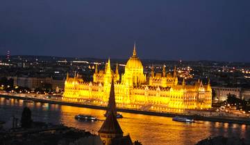 Night view of a lit-up grand building by a river.