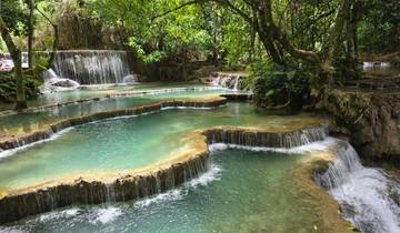 Layered waterfalls with clear blue water in a lush green environment.