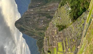 View of Machu Picchu with terraces and high peak.