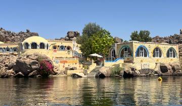Colorful, decorated houses by a river with rocky formations.