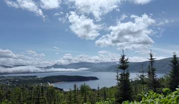 Mountainous landscape with a bay and low clouds.