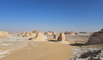 Desert landscape with sand formations and a clear sky.
