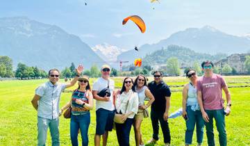 Group of tourists with paragliders in the sky in a mountainous landscape.