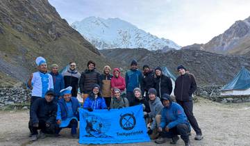 Group of trekkers posing with a snowy mountain backdrop.
