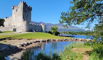 A scenic view of a castle by the lake with mountains in the background.