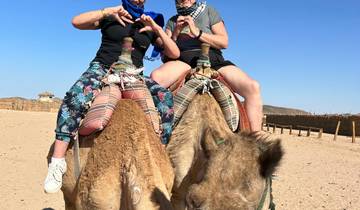 Couple riding camels in the desert.