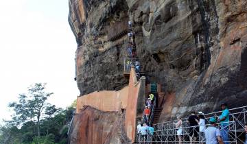 Crowd of tourists climbing a staircase along a cliff.