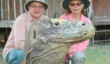 Two people posing with a Komodo dragon.