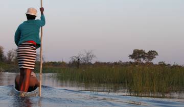 Two people on a canoe in a wetland during sunset.