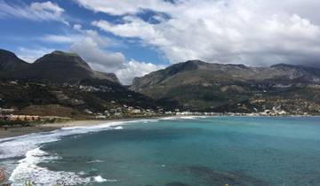 Coastal village surrounded by mountains and blue sea.
